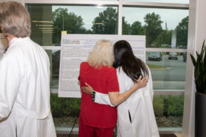 A resident and clinic nurse admiring a research poster the resident worked on,
